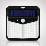A solar-powered outdoor wall light with a black housing, a blue solar panel on top, a white motion sensor, and multiple bright LED light panels on the front, shown against a light gray background.