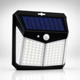 A black solar-powered outdoor wall light with two panels of bright white LED lights and a blue solar panel on top, shown on a light gray background.