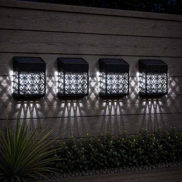 Four solar-powered outdoor lights on a wooden surface with shadows.